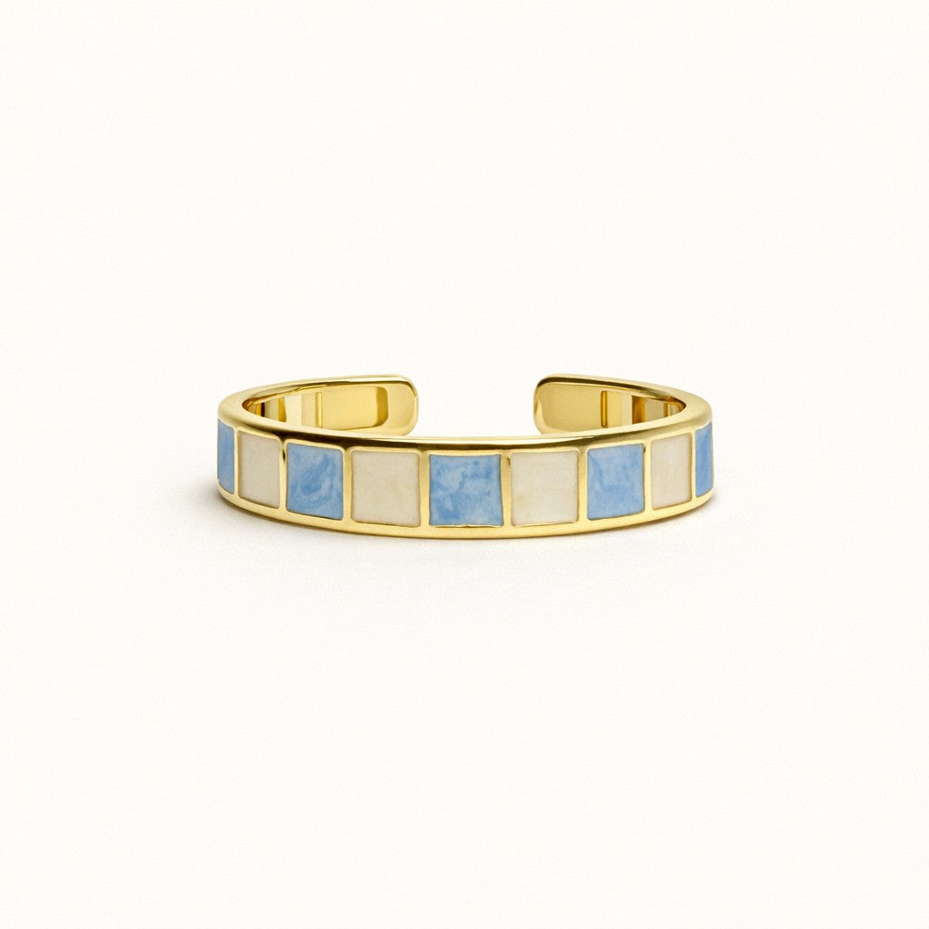 Azure Grid gold-tone open ring with alternating blue and cream square enamel inlays on a white background.