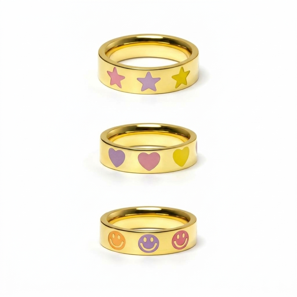 Three gold band rings with pastel enamel motifs: pink, lilac and yellow stars; lilac, pink and yellow hearts; and orange, lilac and pink smiley faces.