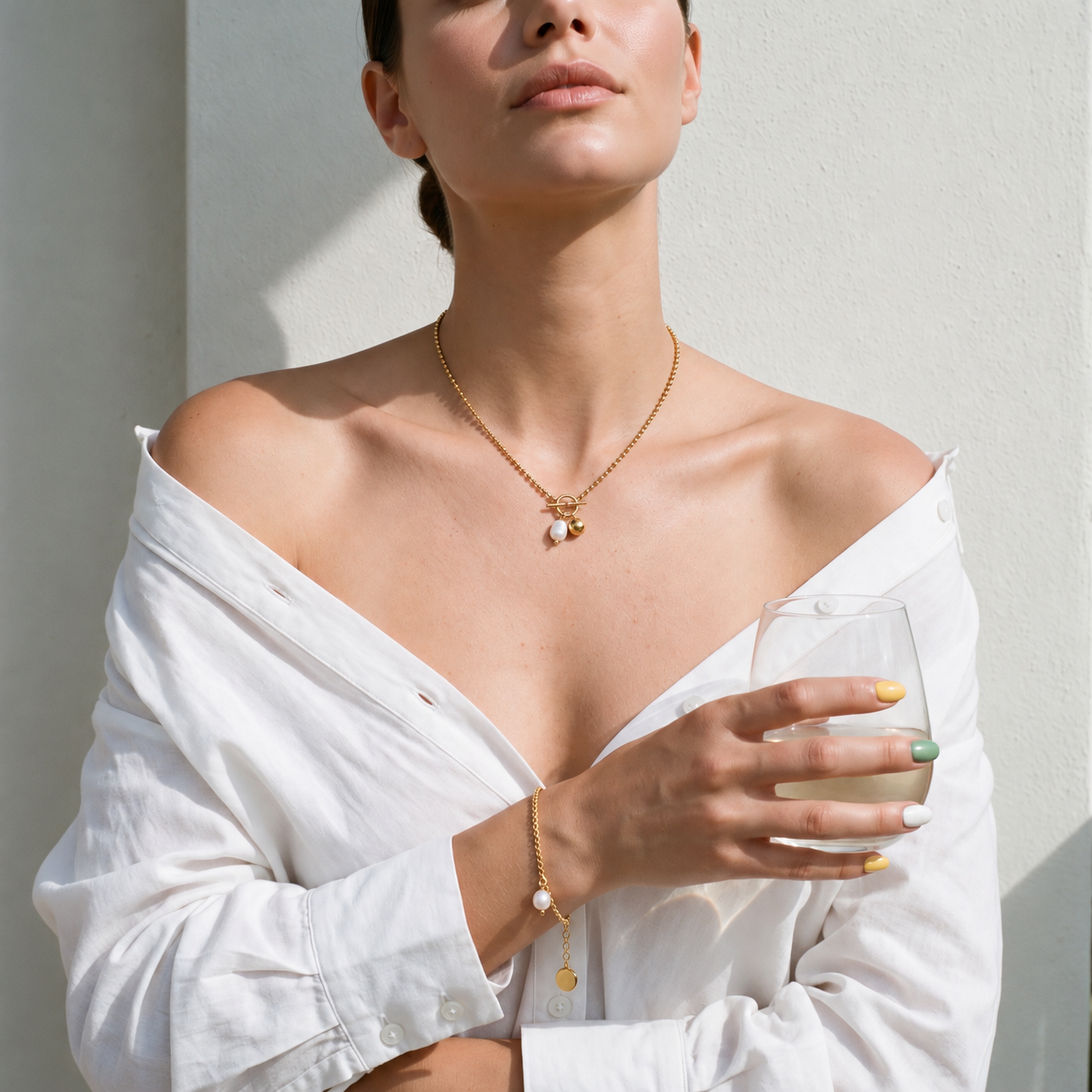 Woman in a white linen shirt wearing the Pearl Promise Necklace and Pearl Promise Bracelet in gold with pearls