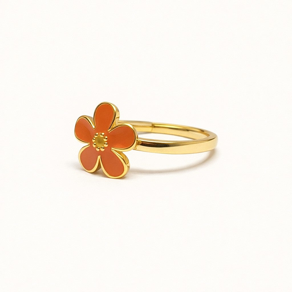 Gold ring with an orange flower-shaped pendant on a white background