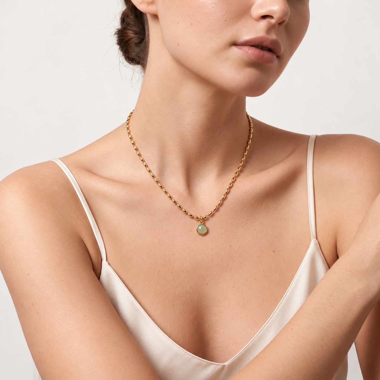Woman in an ivory silk camisole wearing the Celadon Bloom Necklace with a mint-green pendant