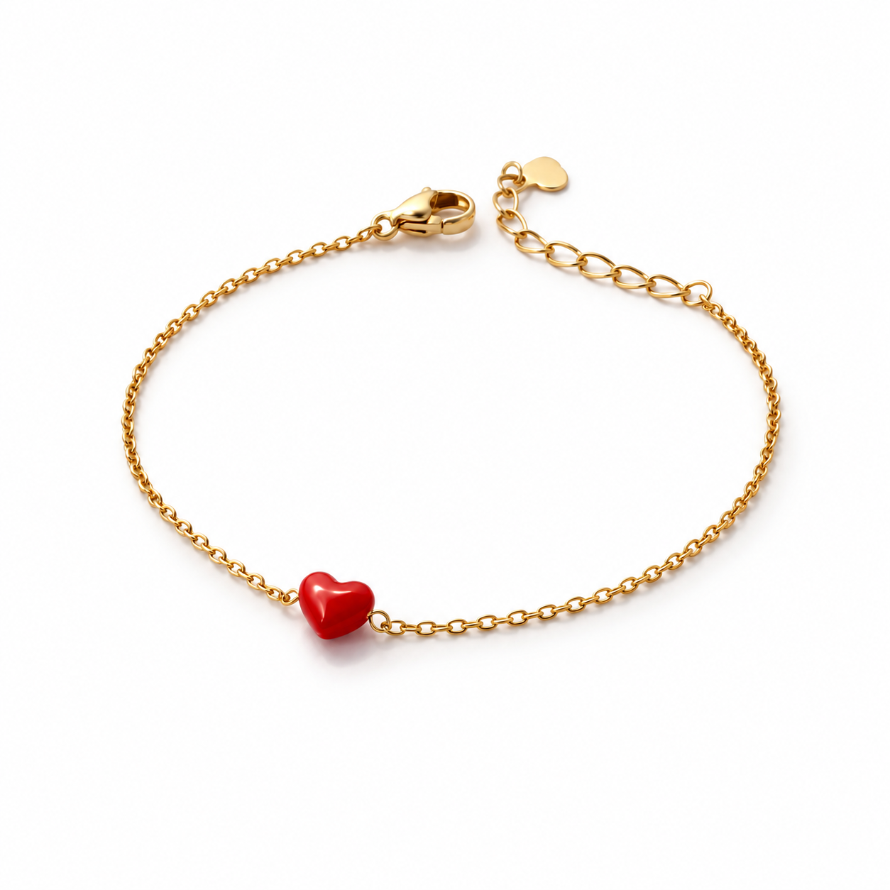 A delicate gold chain bracelet with a small, smooth red heart charm in the center, displayed on a clean white background.