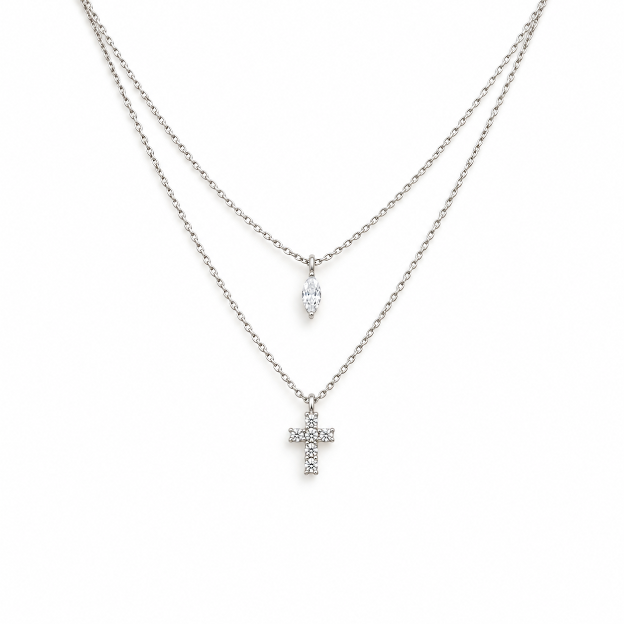 A double-strand silver-tone chain necklace featuring a small marquise-cut clear stone pendant on the top chain and a small cross pendant paved with clear stones on the bottom chain, shown against a plain white background.