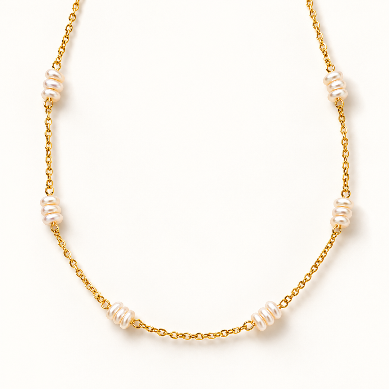 Pearl Moments Necklace, a gold chain with six groups of three small white pearls, on a white background